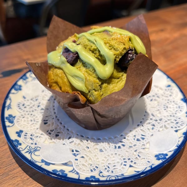 Matcha muffin with chocolate chips and green icing, served on a blue and white plate.