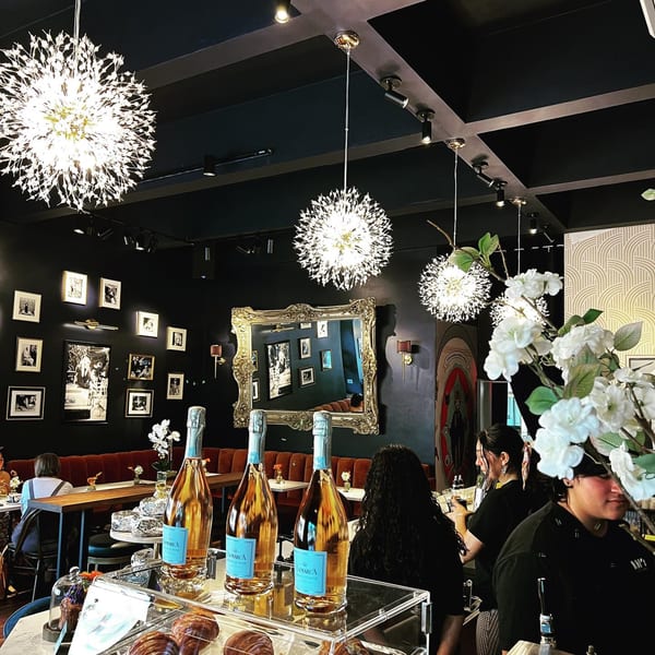 Kiki's Coffee & Spirits interior with sparkling chandeliers, framed photos, and bottles of rosé on the counter.