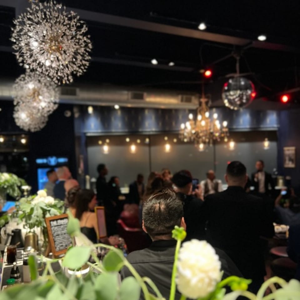A lively Kiki's Coffee & Spirits interior with patrons, sparkling chandeliers, and a disco ball.