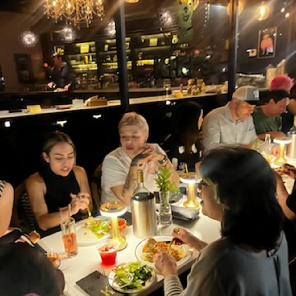 Patrons enjoying food and drinks at tables inside Kiki's Coffee & Spirits, with a bar in the background.