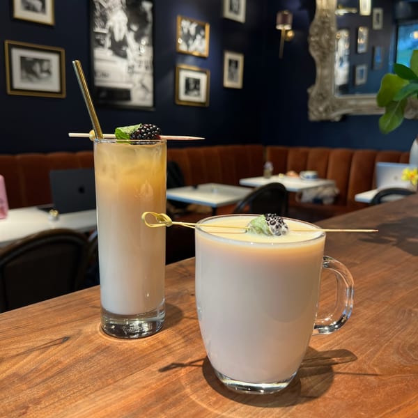 Two Kiki's Coffee & Spirits drinks, one in a tall glass, one in a mug, garnished with blackberries and mint.
